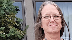a woman with straight gray hair and glasses