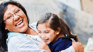 a woman laughs while hugging a young girl