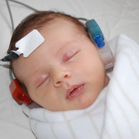 Sleeping newborn wearing newborn screening headphones